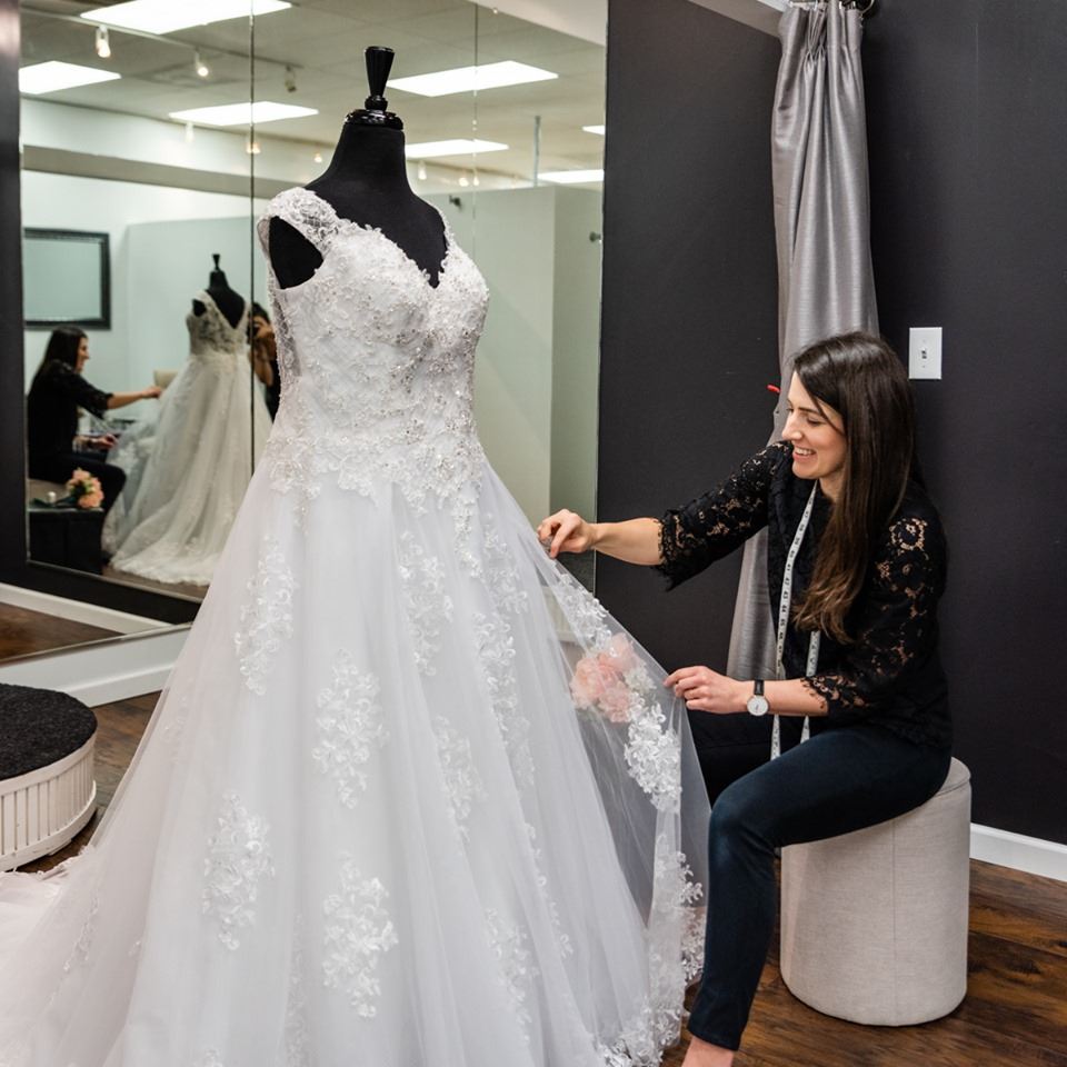 Stylist dressing mannequin in wedding dress